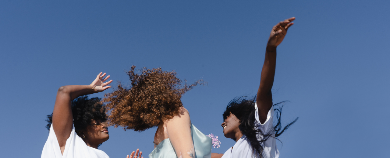 Drei Frauen tanzen vor blauem Hintergrund.